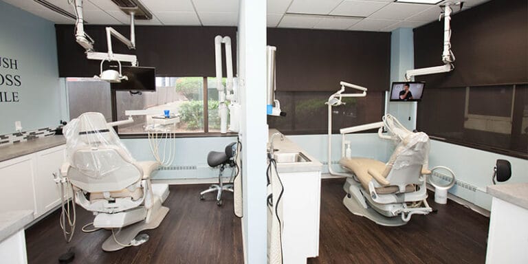 Two dental treatment rooms with chairs and equipment separated by a partition