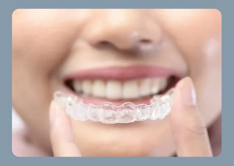Woman holding a clear aligner in front of her smile